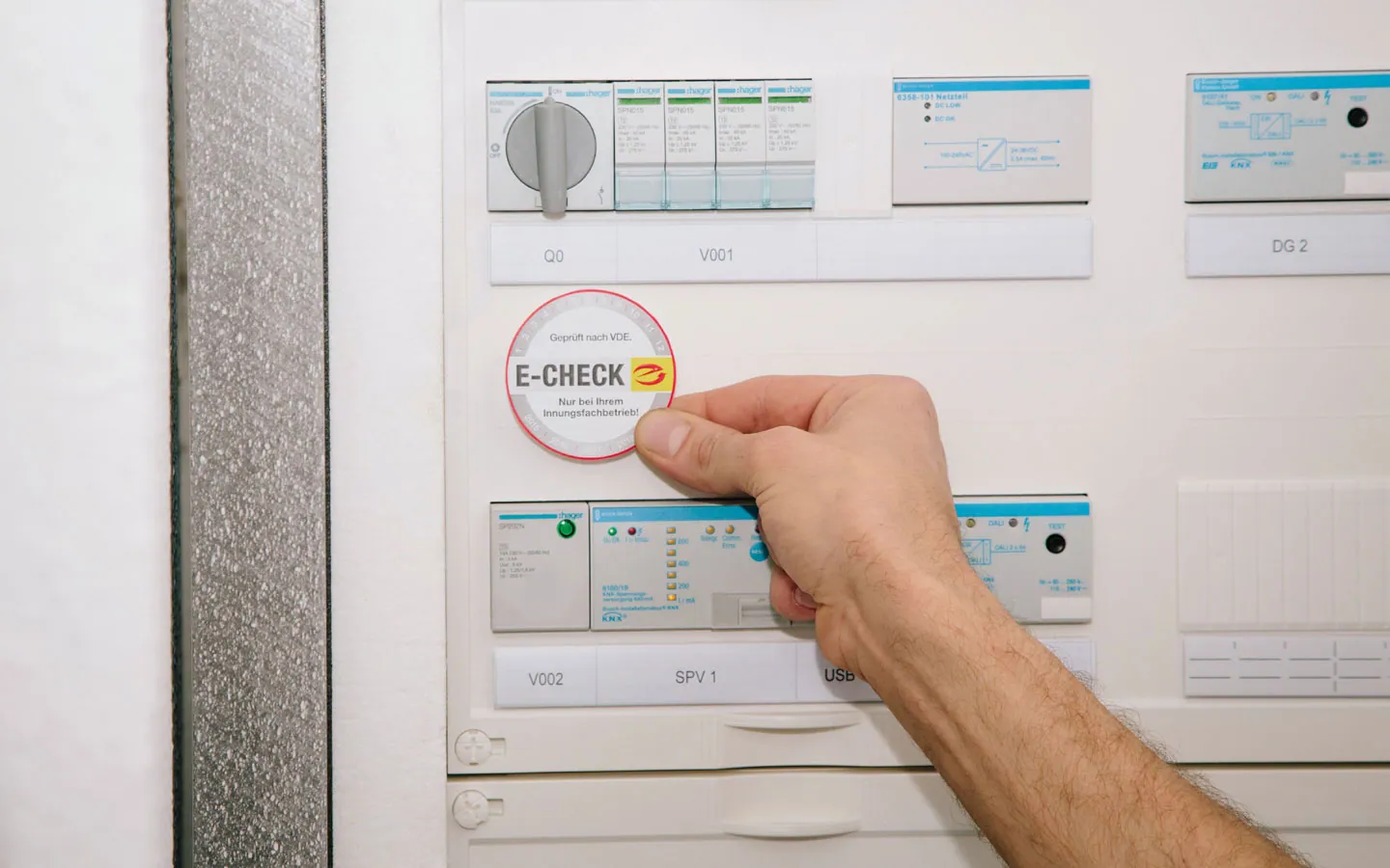 E-CHECK - Mitarbeiter klebt in der Verteilung die E-CHECK Plakette an &middot; Finke Elektro