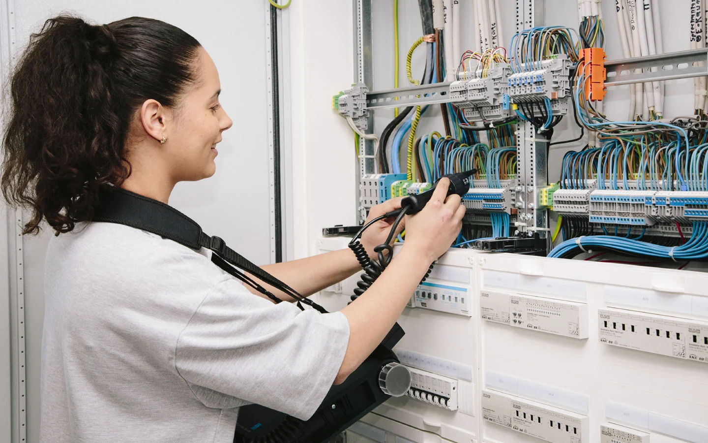 E-CHECK - Mitarbeiterin prüft im Schaltschrank mit einem Meßgerät &middot; Finke Elektro