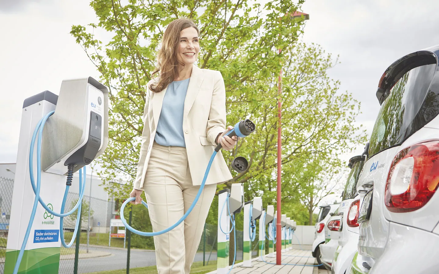 E-Mobilität - Kundin vor Ladestation mit Stecker in der Hand &middot; Finke Elektro